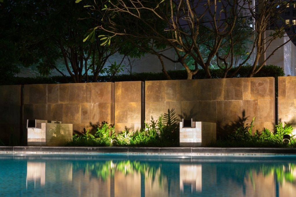 An outdoor lighting installation highlights a swimming pool and garden.